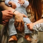 a group of people holding a baby in their hands