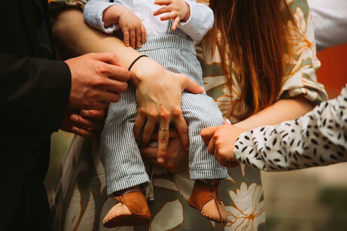 a group of people holding a baby in their hands