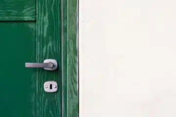 green wooden door beside white wall