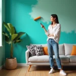 Femme en jeans et blouse blanche peignant un mur turquoise