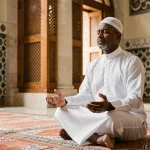 Homme en djellaba blanche en prière sur un tapis dans une mosquée de Lyon pendant le Ramadan